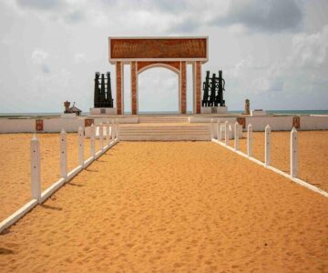 A monument in the shape of an arch on a beach representing the Door of No Return